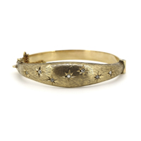 9K Yellow Gold and 0.35ct TDW Diamond, Edwardian Style Bangle. The bangle is stamped Birmingham 1990. The band features a flower patterned and textured top with stars that have centres of, 7 old mine and round brilliant cut, Diamonds (0.35ct TDW, G-I colour, SI clarity), bead set. The bangle is hinged with spring tongue clasp and safety chain attached. Condition: Pre-Owned.

Insurance Valuation Provided by Vendor: $6,000.00
, HE - 509